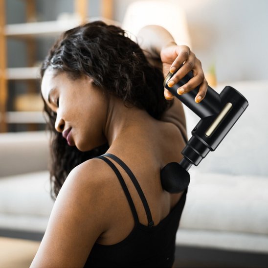Femme utilisant pistolet de massage sur dos et épaules
