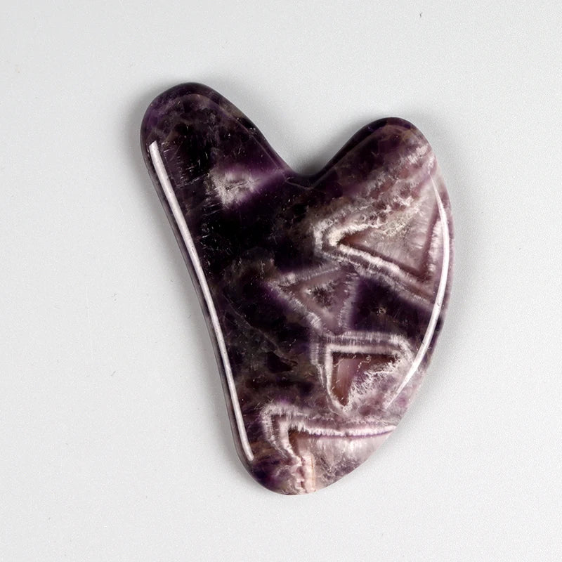 Gua sha en améthyste violette en forme de cœur.