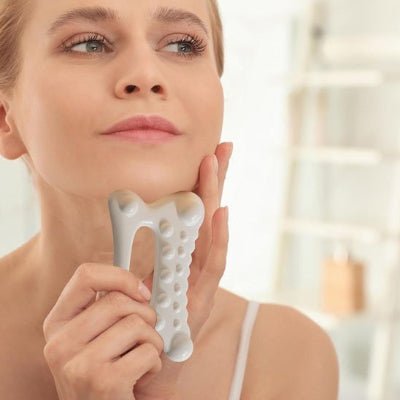 femme utilisant gua sha, outil de massage moderne machoire