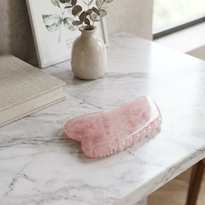 Gua sha quartz rose dente sur table